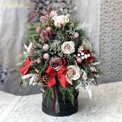 Christmas arrangement with roses, pinecones, and red ribbons in a black box
