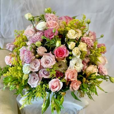 Large bouquet of pink, white, and cream roses with yellow filler flowers