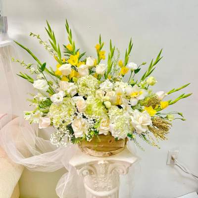 Large white and yellow floral arrangement in a wooden container