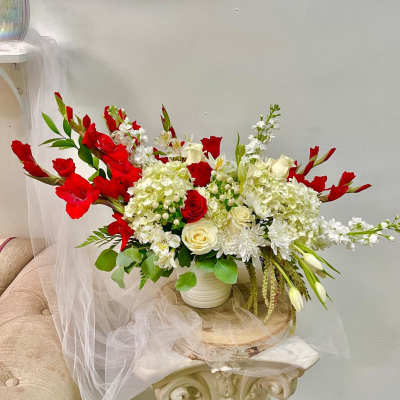Large red and white floral arrangement in a white vase