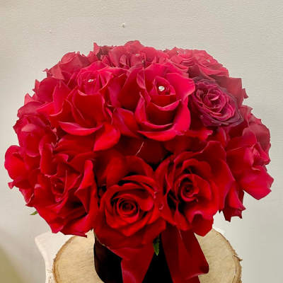 Red rose bouquet in a black vase with a red ribbon
