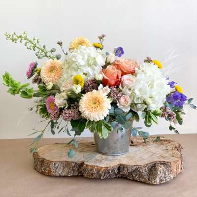 Mixed bouquet of roses, hydrangeas, and daisies in a metal bucket