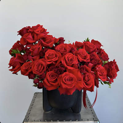 Red rose arrangement in a black vase