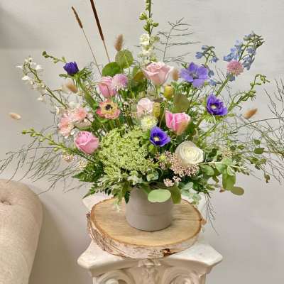 Loose pastel bouquet in a white vase with pink, purple, and white blooms