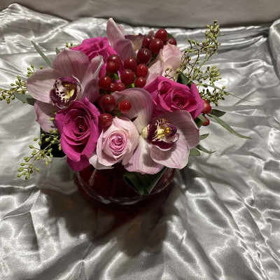 Pink roses and orchids arranged in a red vase