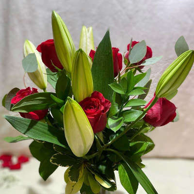 Red roses and unopened lily buds in a glass vase