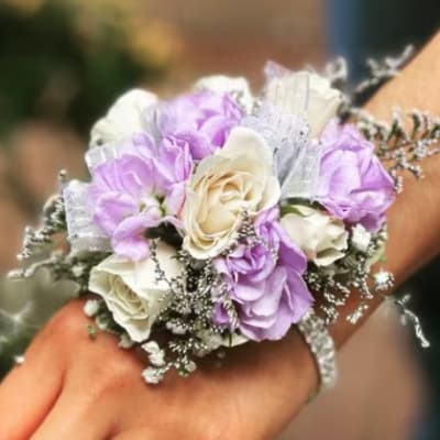 Wrist corsage with lavender and white roses on a hand