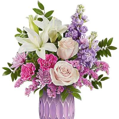 Bouquet of white lilies, pink roses, and purple flowers in a lavender vase