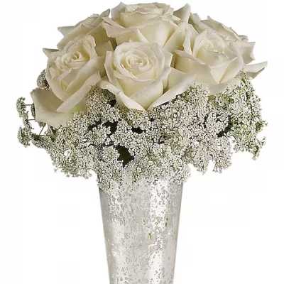 White roses arranged in a tall clear vase with baby's breath