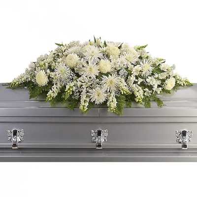 White funeral casket spray with mixed blooms on a silver casket