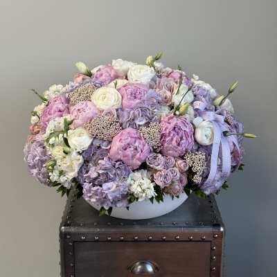 Large pastel bouquet of pink, lavender, and white flowers in a white bowl