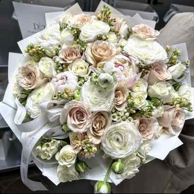 Bouquet of white and blush roses with ranunculus wrapped in white paper