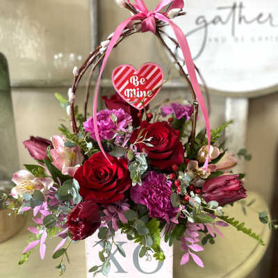 Heart-themed flower basket with red roses and pink blooms