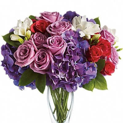 Bouquet of purple, pink, red, and white flowers in a clear glass vase
