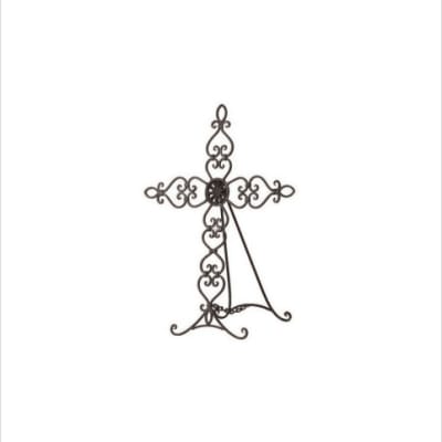 Ornate black metal standing cross with scrollwork on an easel base.