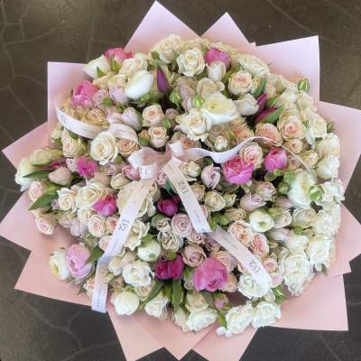 Large bouquet of pink and white roses wrapped in pale pink paper