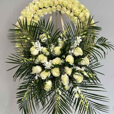 White rose funeral wreath with palm fronds and white orchids