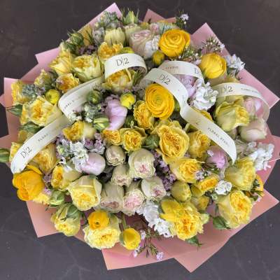 Large bouquet of yellow and pale pink roses wrapped in pink paper