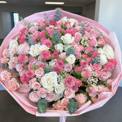 Large bouquet of pink and white roses wrapped in pink paper