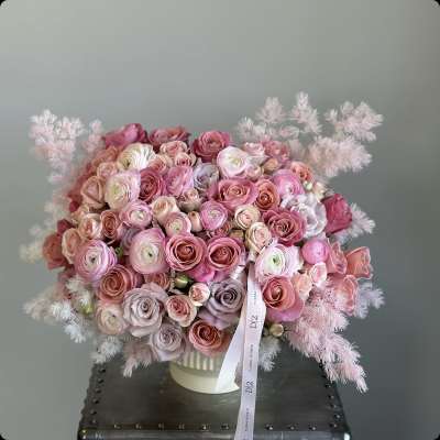 Pink and blush rose bouquet in a white vase with feathery accents