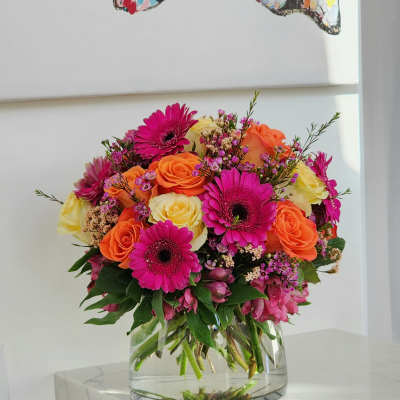 Bright mixed bouquet of roses and gerbera daisies in a clear glass vase