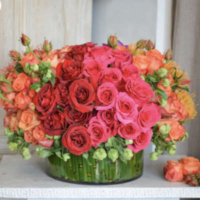 Round bouquet of pink, red, and peach roses in a glass vase