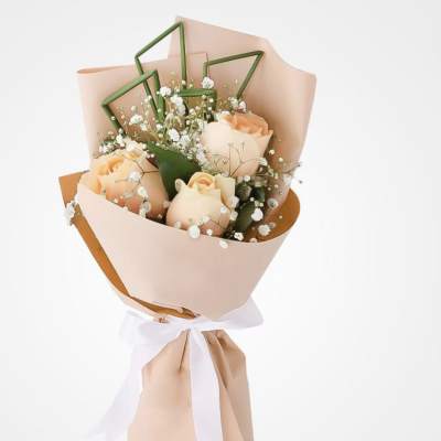 Peach roses wrapped in blush paper with a white ribbon