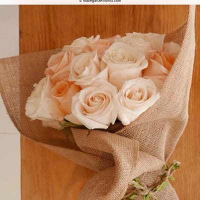 Bouquet of pale peach and white roses wrapped in burlap