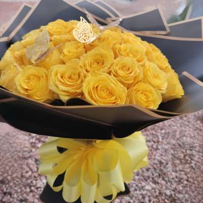 Bouquet of yellow roses wrapped in black paper with a yellow ribbon