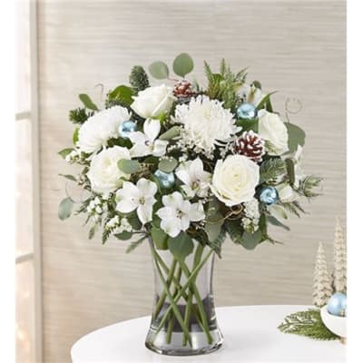 White floral arrangement in a clear glass vase with blue ornaments