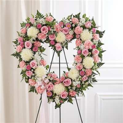 Heart-shaped floral wreath with pink and white flowers on a stand