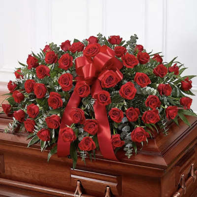 Red rose casket spray with a large red ribbon bow