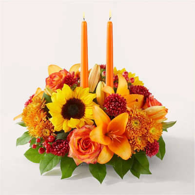 Orange candle centerpiece with sunflowers, roses, lilies, and chrysanthemums
