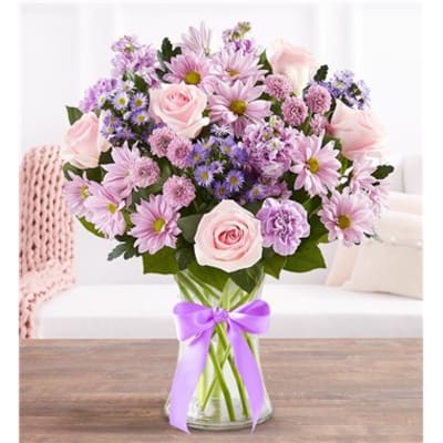 Pink and lavender bouquet in a glass vase with a purple ribbon
