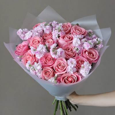 Pink rose bouquet with pale filler flowers wrapped in translucent paper