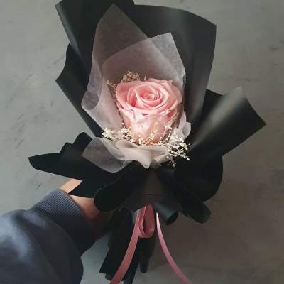 Single pink rose wrapped in black paper with a pink ribbon