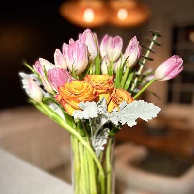 Pink tulips and orange roses in a clear glass vase