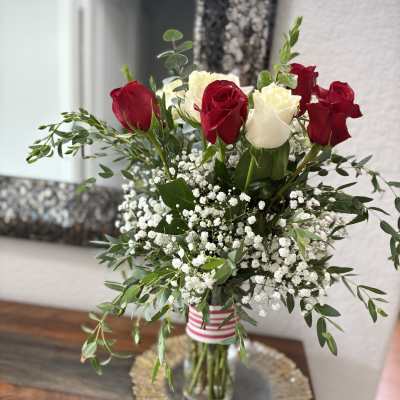 Red and white roses in a glass vase with baby's breath