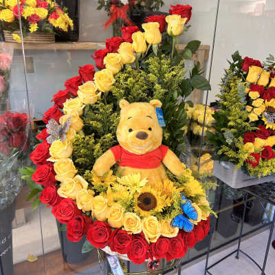 Large rose arrangement with a Winnie the Pooh plush and yellow flowers