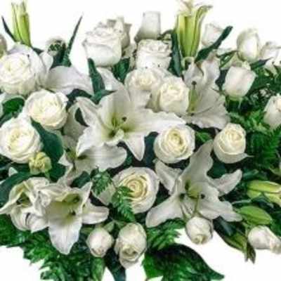 Long white arrangement of roses and lilies in an elongated spray style