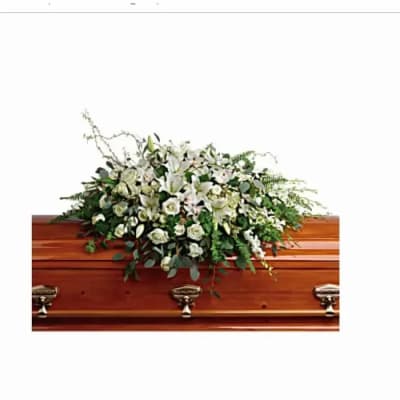 White lily and rose casket spray on a polished wooden casket