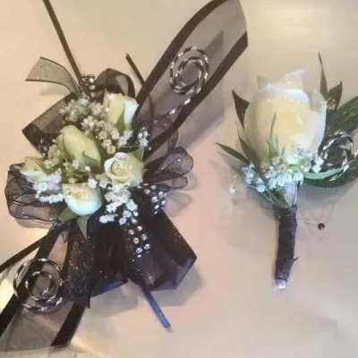 White rose corsage and boutonniere with black ribbon, rhinestones, and small white filler flowers