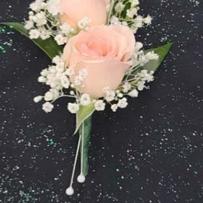 Peach rose boutonniere with white filler flowers on a black speckled background