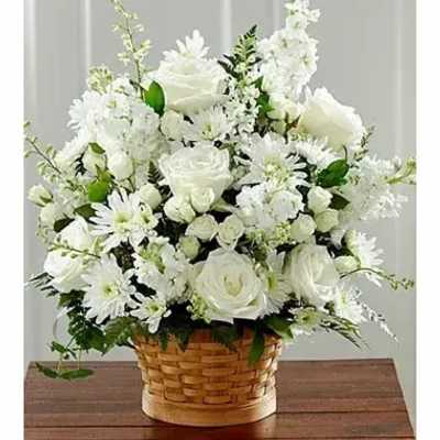 White roses and daisies arranged in a basket on a wooden table