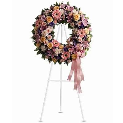 Floral wreath on a white stand with a pink ribbon bow