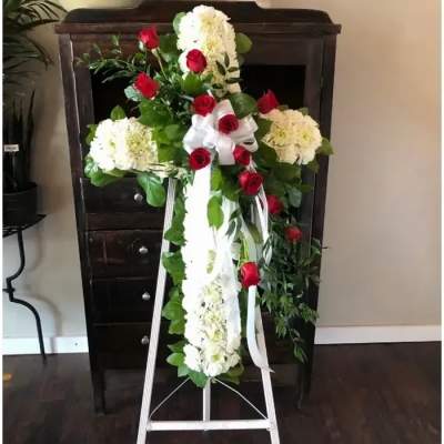Standing floral cross with red roses and white flowers on an easel