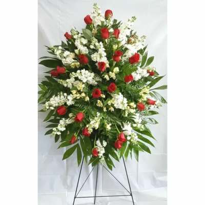 Standing spray of red roses and white flowers on a metal easel