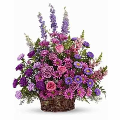 Purple and pink mixed flower arrangement in a wicker basket