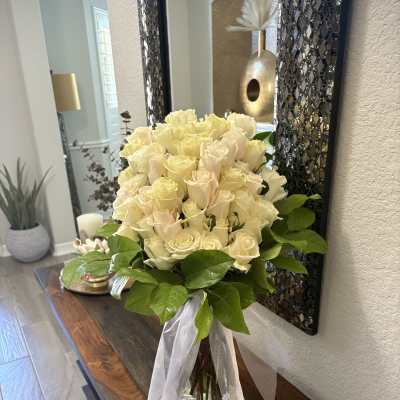 Bouquet of cream roses in a glass vase with a white ribbon