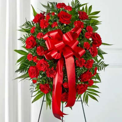 Tall red rose and carnation standing spray with large red bow on an easel